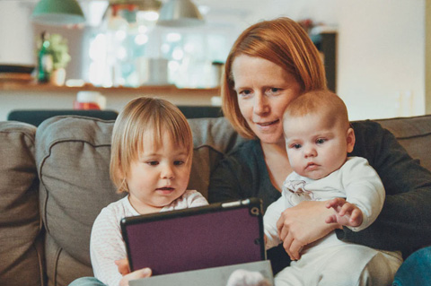 Mujer mirando un dispositivo con con sus hijos