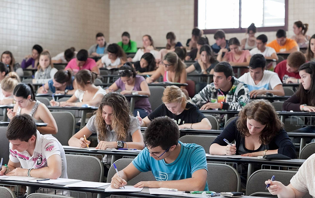 Fotografía de alumnos en un aula realizando un examen.